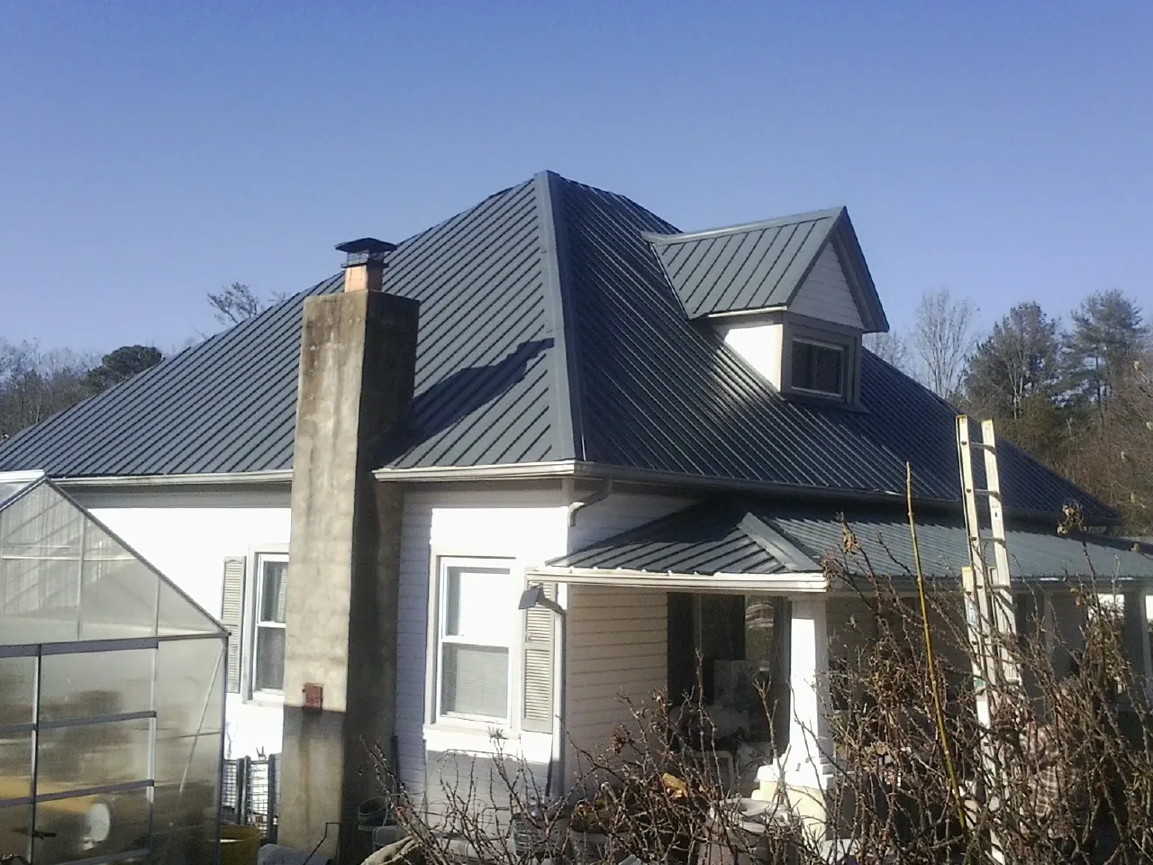 Dark blue standing seam metal roof on a white farmhouse with dormer — Slate & Tile Roof Repair by Roofing Brothers in Lanoka Harbor