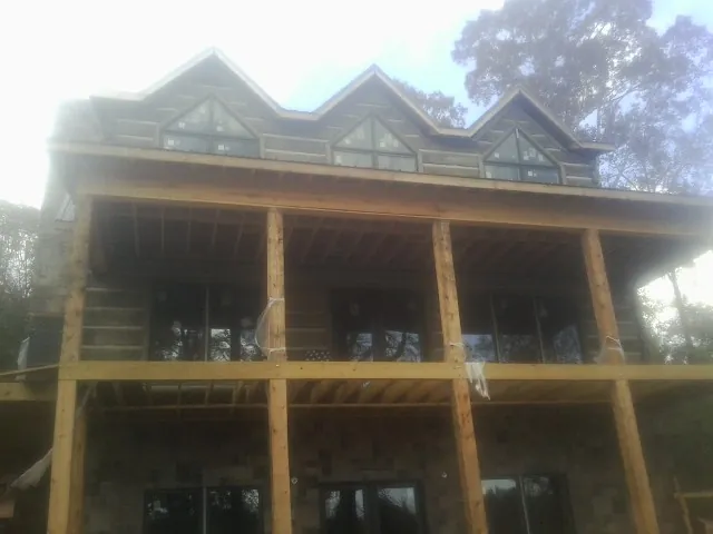 Dormers and porch framing on a large log home under construction — Roof Coating work by our crew in Lanoka Harbor