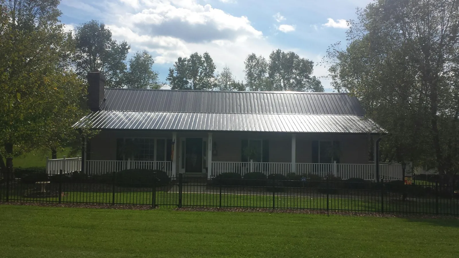 Gray metal roof on a brick ranch with a full width front porch — Gutter Guard Installation work by our crew in Lanoka Harbor