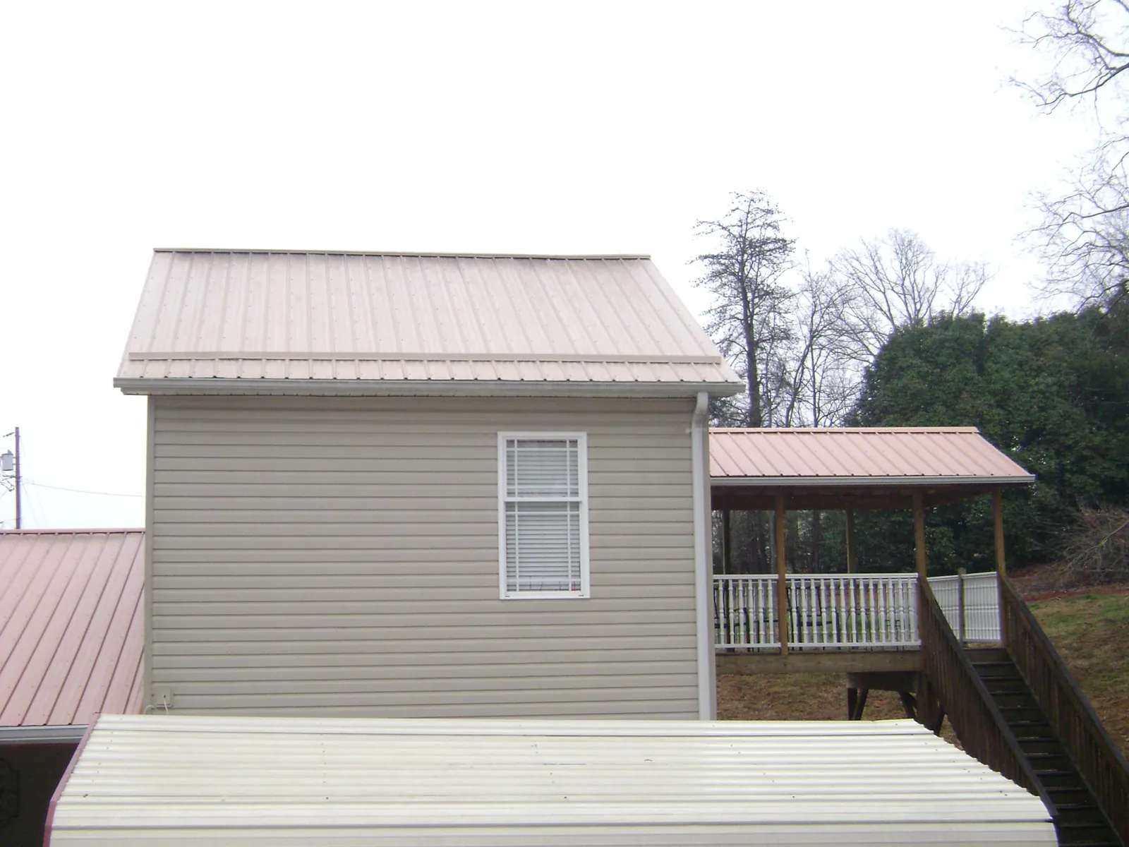 Tan metal roofs on a two story addition and attached porch, from a Roof Replacement job in Lanoka Harbor