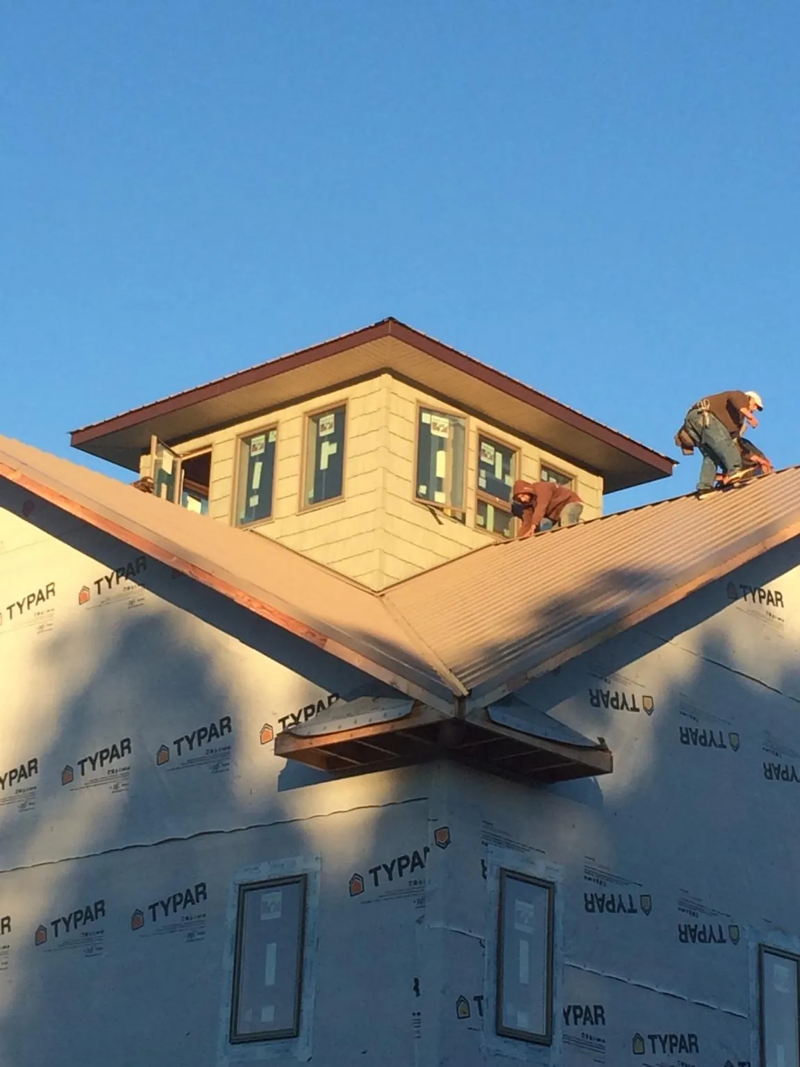 Roofers working around a rooftop cupola on a new metal roof at sunset — Roof Waterproofing in Lanoka Harbor by Roofing Brothers